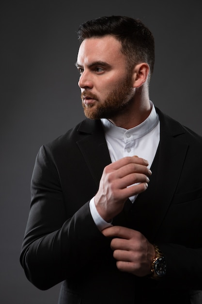 Un hombre guapo con traje negro y camisa blanca.