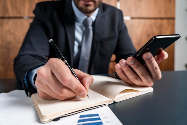 Un hombre guapo en traje tomando notas usa el teléfono Concepto de éxito Vestimenta formal