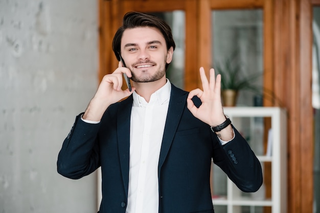 Hombre guapo en traje usa el teléfono en la oficina