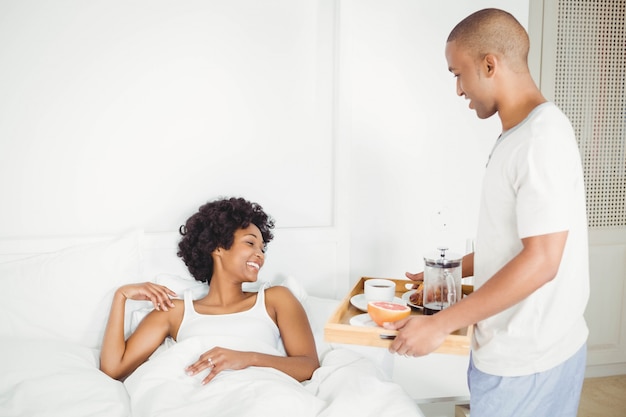 Hombre guapo trayendo el desayuno a su novia en la cama