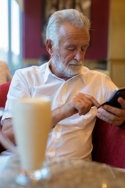 Foto hombre guapo turista senior relajante dentro de la cafetería.