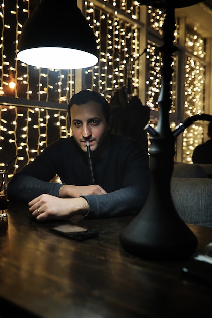 Hombre guapo con vaso de alcohol con hielo en un club nocturno