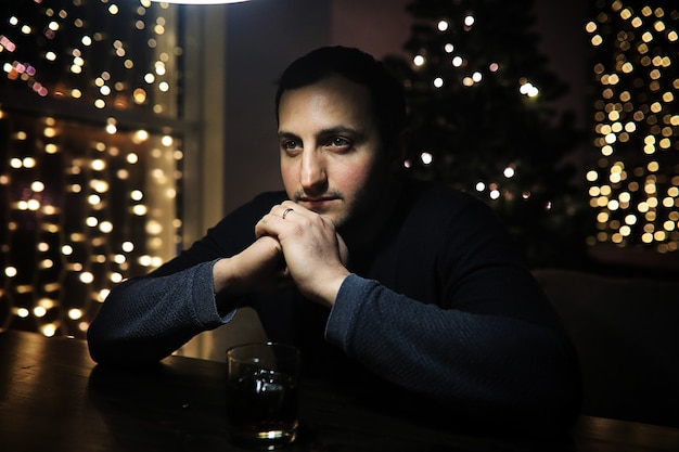 Hombre guapo con vaso de alcohol con hielo en un club nocturno