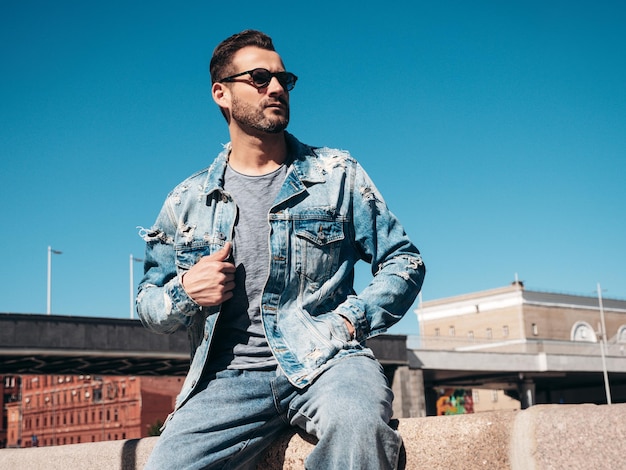 Hombre guapo vestido con una chaqueta de vaqueros Hombre de moda posando en la calle
