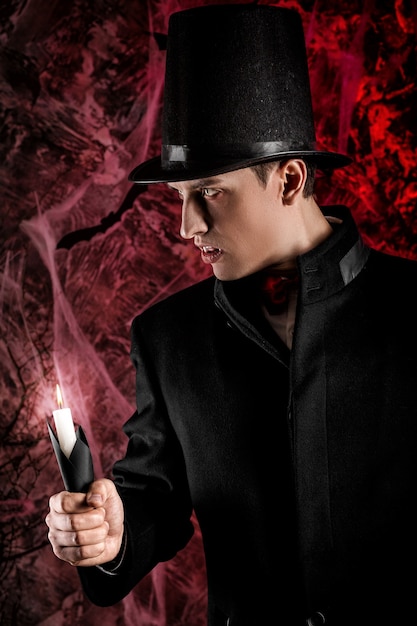 Hombre guapo vestido con un disfraz de Drácula para Halloween. vampiro atractivo con velas