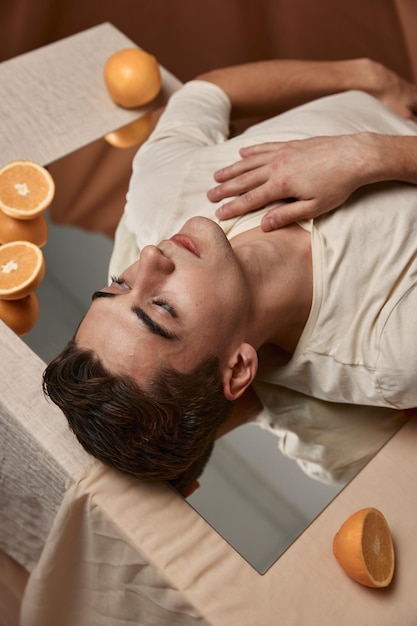 Foto un hombre guapo yace sobre la mesa en el espejo con los ojos cerrados.