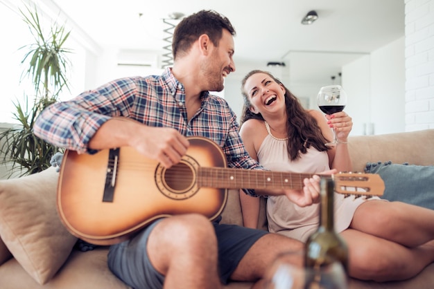 Hombre con guitarra acústica cantando para mujer sonriente