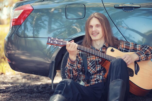 Un hombre con una guitarra en un día de verano al aire libre.