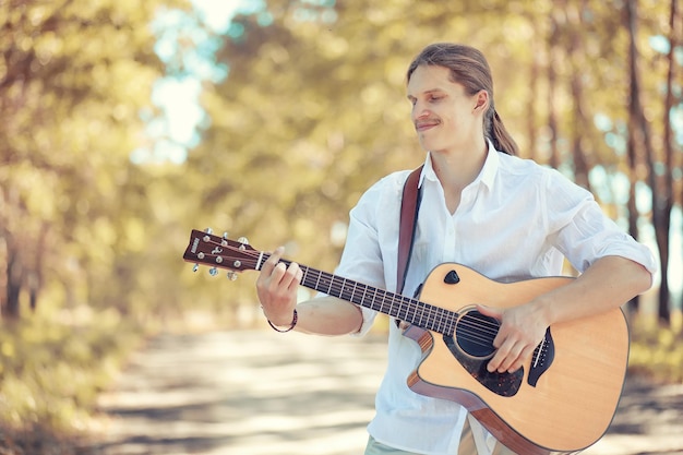 Un hombre con una guitarra en un día de verano al aire libre.