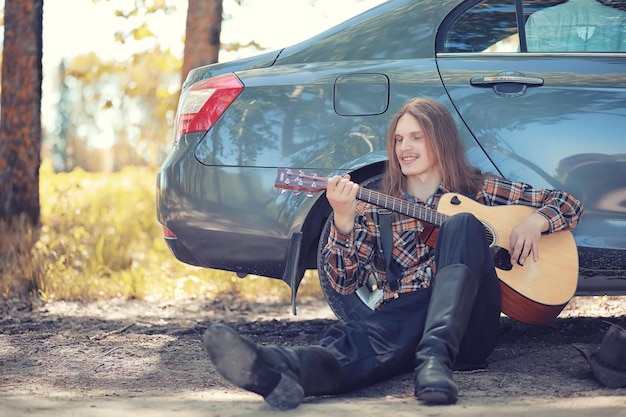 Un hombre con una guitarra en un día de verano al aire libre.