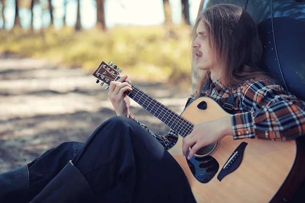 Un hombre con una guitarra en un día de verano al aire libre.