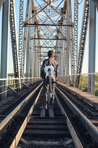 Un hombre con una guitarra eléctrica en el paisaje industrial al aire libre