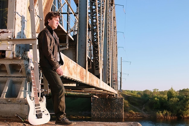 Un hombre con una guitarra eléctrica en el paisaje industrial al aire libre