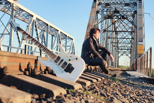 Un hombre con una guitarra eléctrica en el paisaje industrial al aire libre
