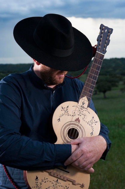 Hombre con guitarra de pie contra el cielo
