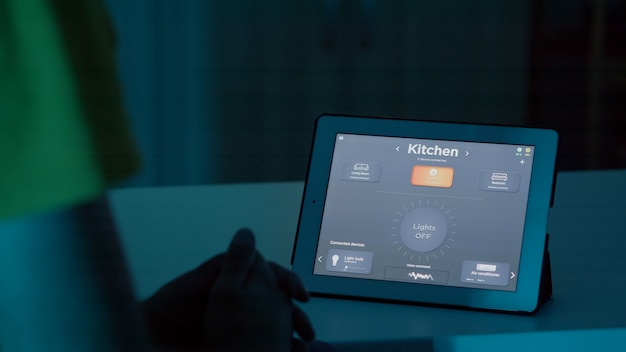 Hombre hablando con asistente de voz en tableta en sistema de automatización del hogar inteligente