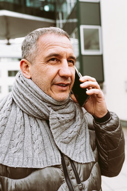 Un hombre hablando por teléfono con una bufanda gris.