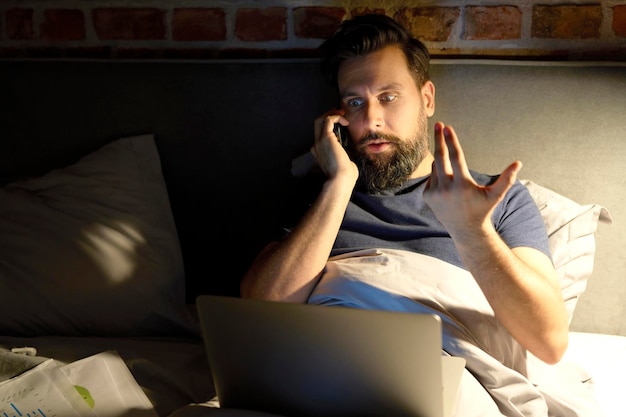 Hombre hablando por teléfono en la cama por la noche