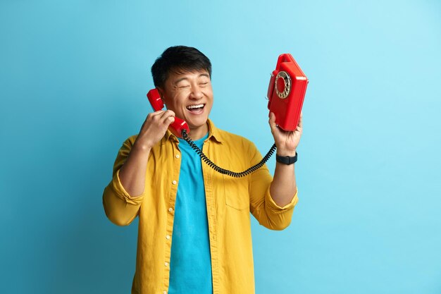 Foto hombre hablando por teléfono fijo hombre asiático hablando por teléfono retro y sonriendo