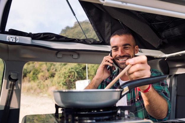 Hombre hablando por teléfono mientras cocina en su furgoneta