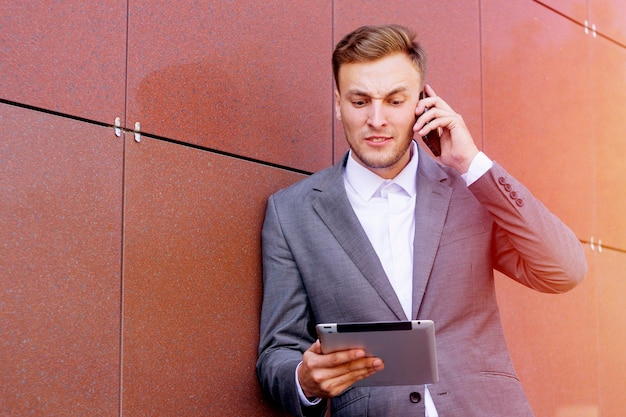 Hombre hablando por teléfono mientras usa tableta