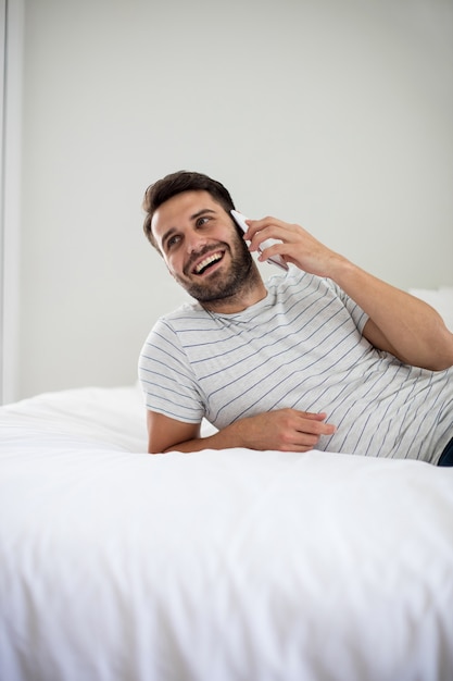 Foto hombre hablando por teléfono móvil en el dormitorio en casa