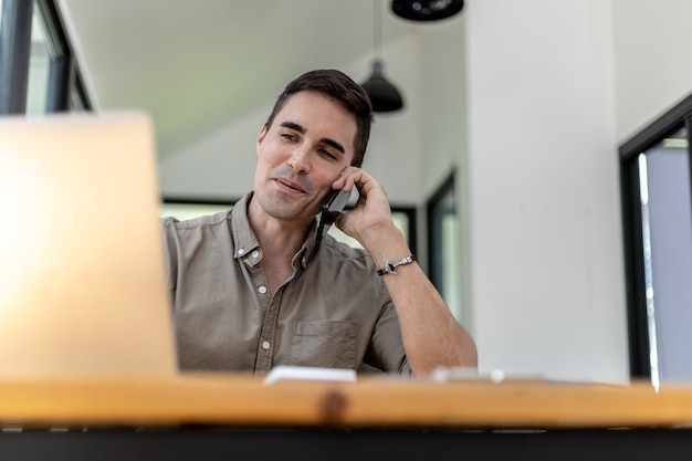 Hombre hablando por teléfono en la oficina, es un empresario ejecutivo de una empresa nueva fundada con socios, es un ejecutivo joven y enérgico y las ganancias de la empresa continúan creciendo.