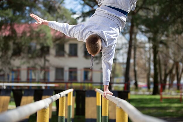 Foto un hombre hace ejercicios en barras asimétricas en la calle un hombre practica deportes