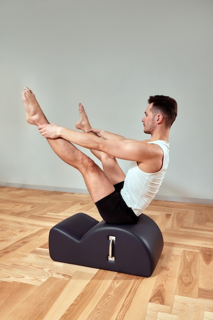 Foto un hombre hace ejercicios en un reformador de pilates un reformador de gimnasia de pilates un turnagger reclinado para entrenar los músculos abdominales