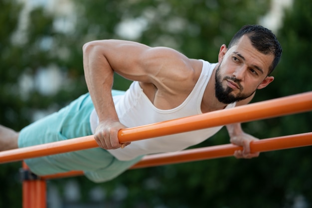 Un hombre hace flexiones en los bares de la calle en el día