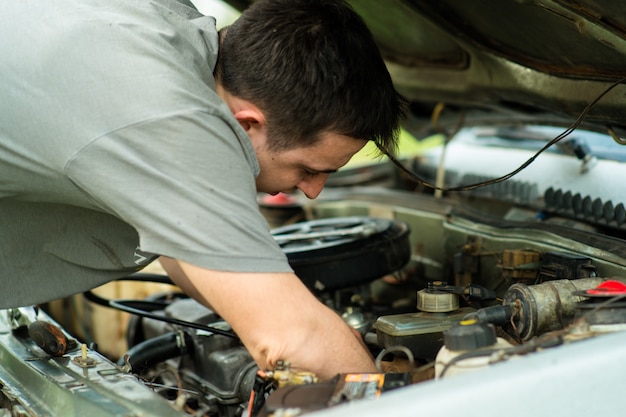 El hombre hace reparación de automóviles debajo del capó