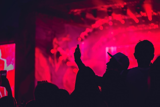 Un hombre hace una selfie en el fondo de un concierto de rock.