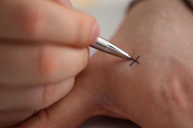 Hombre hace x nota con cruz con pluma en mano closeup