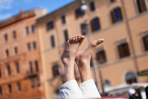 Un hombre hace yoga y se para con los pies en la calle.