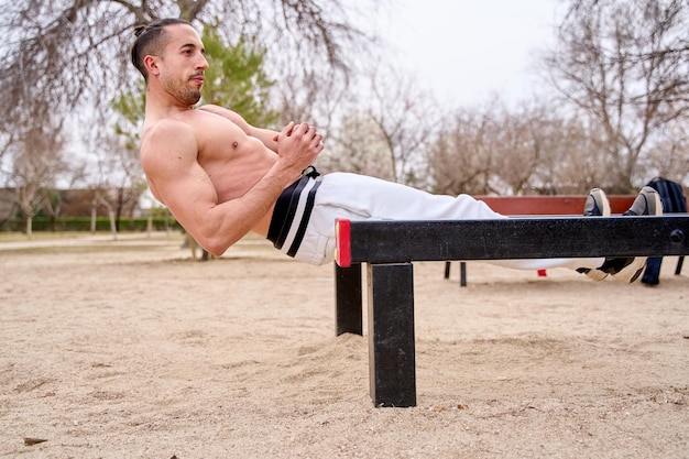 Hombre haciendo abdominales en el parque de entrenamiento callejero