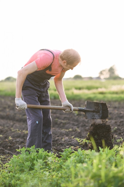 Foto hombre haciendo un agujero para plantar flores en el jardín.