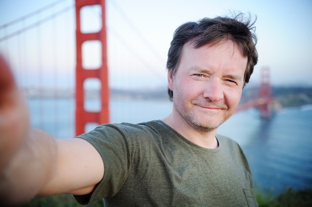 Hombre haciendo un autorretrato (selfie) con el famoso puente Golden Gate en San Francisco, California, EE. UU.