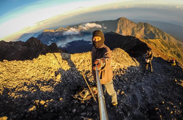 Foto hombre haciendo clic en selfie mientras está de pie en la montaña