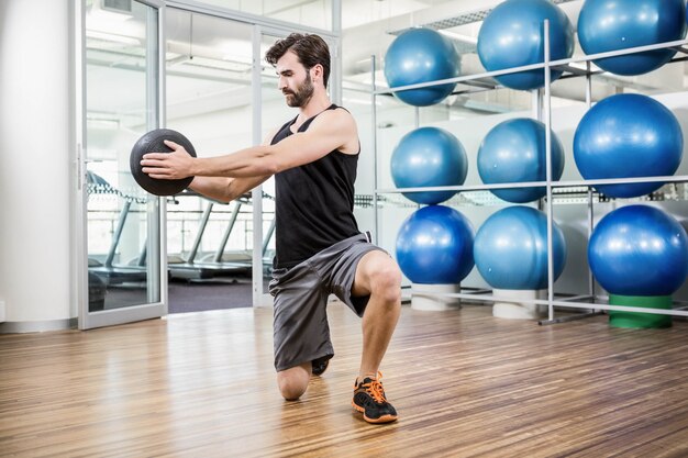 Hombre haciendo ejercicio con balón medicinal en el estudio