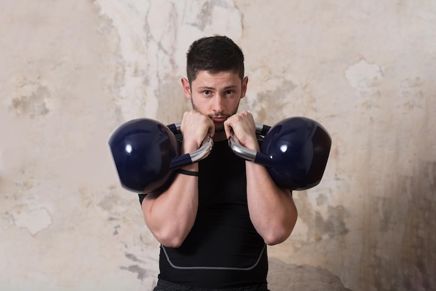 Hombre haciendo ejercicio con Kettle Bell y flexionando los músculos Muscular culturista atlético Ejercicios de modelo de fitness