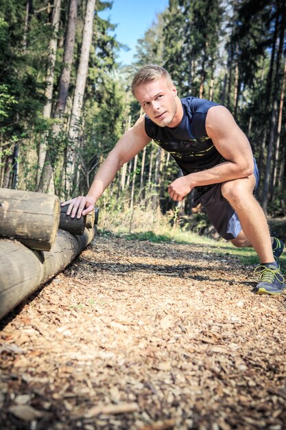 Hombre haciendo ejercicio en un tronco en el bosque