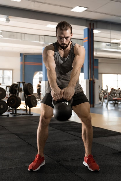 Hombre haciendo ejercicios con pesas rusas en el gimnasio