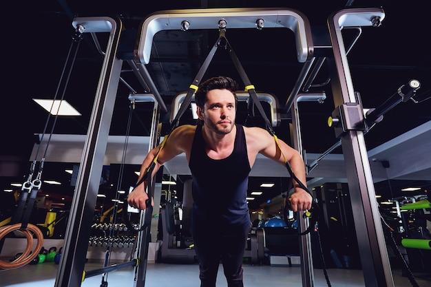 Foto un hombre está haciendo ejercicios en el simulador en el gimnasio.