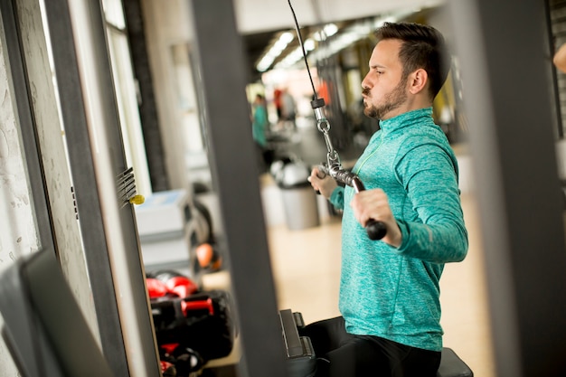 Foto hombre haciendo excersise en una máquina lat en el gimnasio