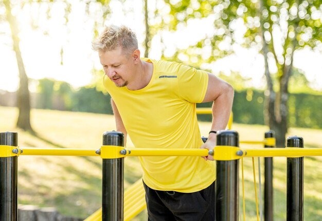 Hombre haciendo flexiones con barra horizontal al aire libre en el parque para un bienestar saludable Deportista haciendo ejercicio fuerte para los músculos