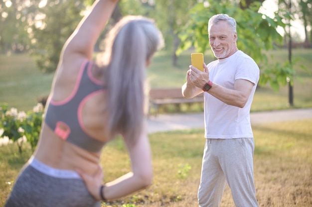 Foto un hombre haciendo una foto de su esposa mientras ella hace ejercicio.