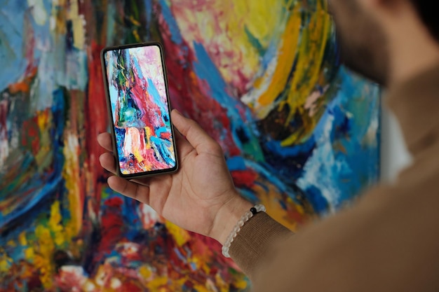 Foto hombre haciendo fotos de pintura en smartphone