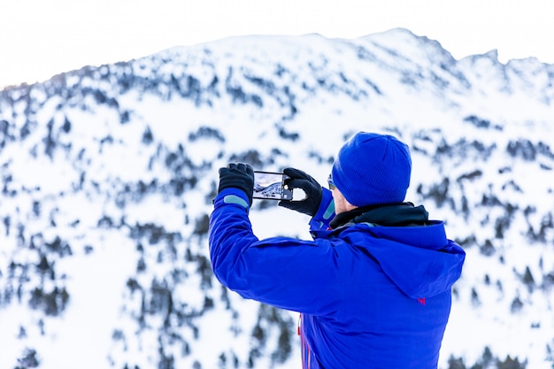 Hombre haciendo fotos con su teléfono en la nieve.