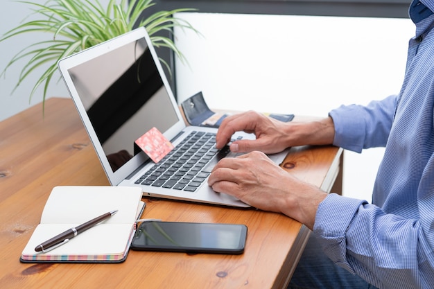 Foto hombre haciendo pagos en línea frente a la computadora.