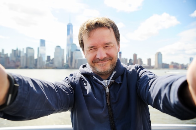 Foto hombre haciendo selfie con los rascacielos de manhattan en la ciudad de nueva york